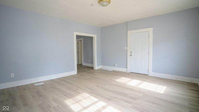 unfurnished room with light wood finished floors, visible vents, and baseboards