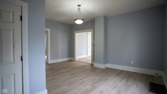 unfurnished room featuring light wood-style flooring, visible vents, and baseboards