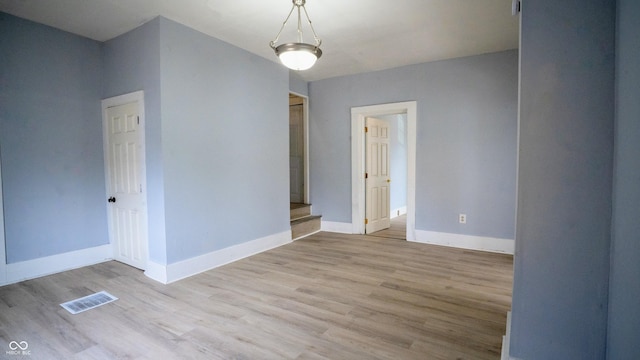 spare room featuring visible vents, baseboards, and wood finished floors