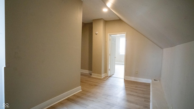 bonus room featuring light wood-type flooring, visible vents, lofted ceiling, and baseboards