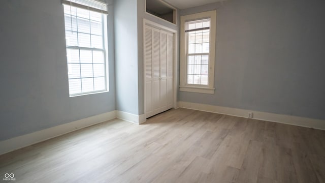 unfurnished bedroom featuring light wood finished floors, a closet, and baseboards