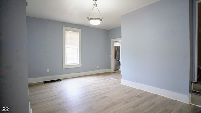 unfurnished room with baseboards, visible vents, and light wood-style floors