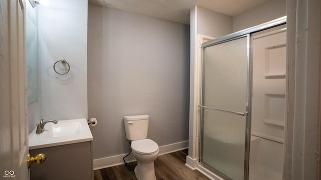 bathroom with toilet, wood finished floors, vanity, baseboards, and a stall shower