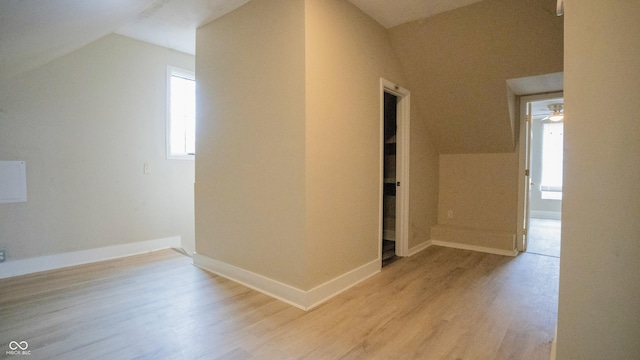 bonus room with light wood-style floors, vaulted ceiling, and baseboards