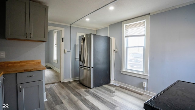 kitchen with gray cabinets, stainless steel refrigerator with ice dispenser, wood counters, and light wood-style floors