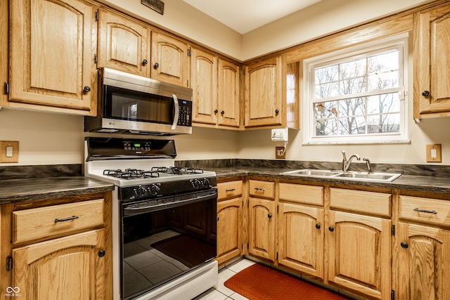 kitchen featuring light tile patterned floors, white gas stove, and sink