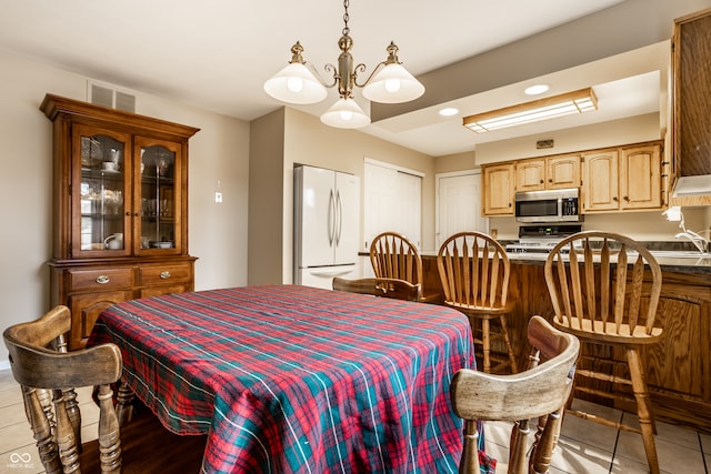 tiled dining area featuring a chandelier and sink