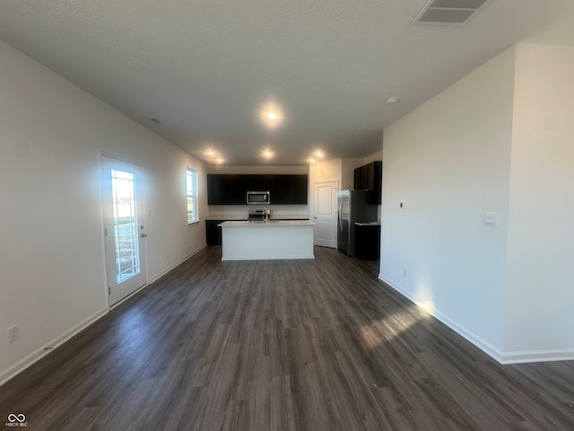 kitchen featuring dark hardwood / wood-style flooring, a kitchen island with sink, and appliances with stainless steel finishes