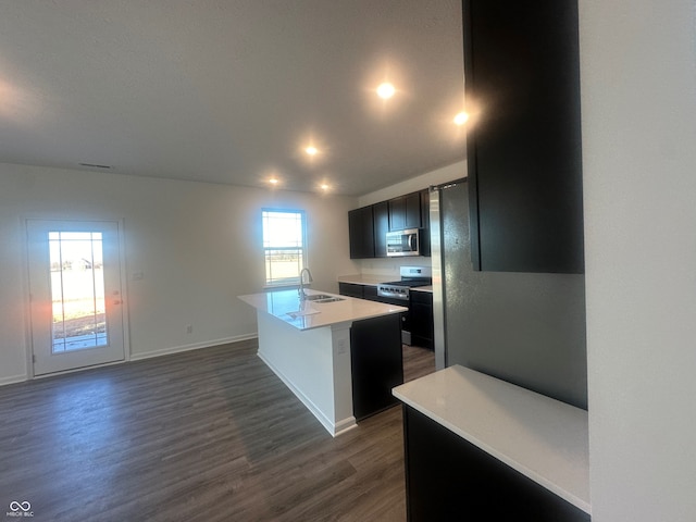 kitchen with a center island with sink, dark hardwood / wood-style floors, gas range oven, and sink