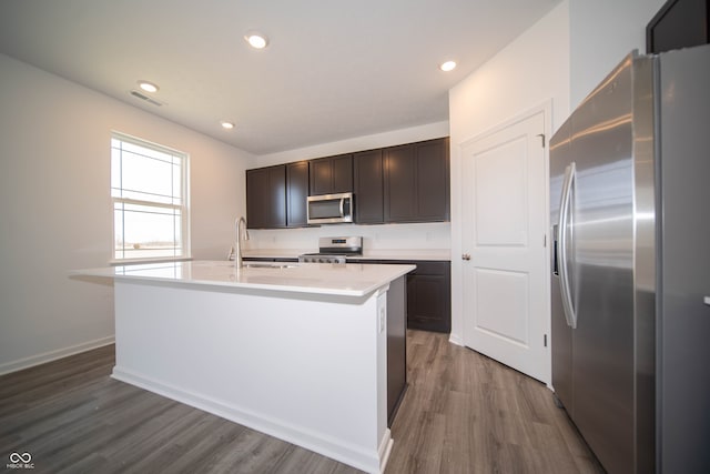 7904 Magnolia St, New Palestine, IN 46163 - kitchen featuring stainless steel appliances, a sink, dark wood finished floors, light countertops, and a center island with sink