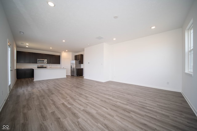 7904 Magnolia St, New Palestine, IN 46163 - unfurnished living room featuring wood finished floors, baseboards, recessed lighting, and a sink
