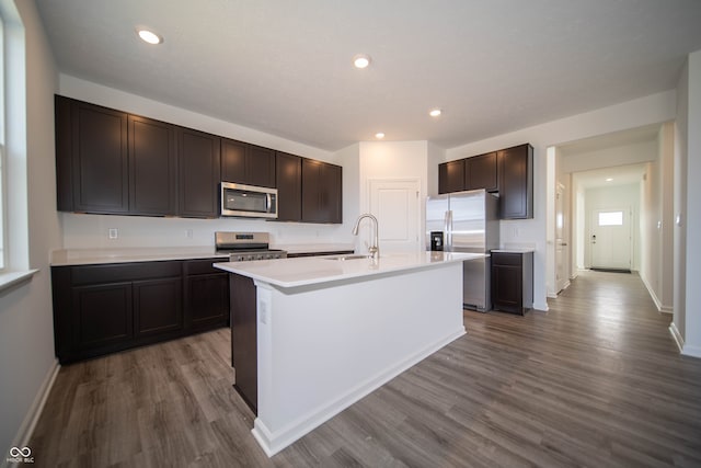 7904 Magnolia St, New Palestine, IN 46163 - kitchen featuring appliances with stainless steel finishes, a sink, dark wood finished floors, an island with sink, and dark brown cabinetry
