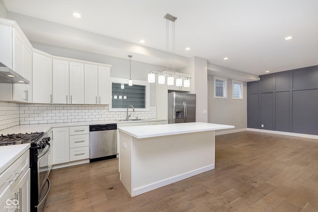 kitchen with a center island, sink, white cabinetry, wood-type flooring, and stainless steel appliances