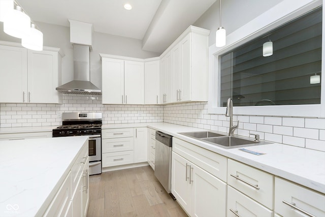 kitchen with white cabinets, sink, light wood-type flooring, appliances with stainless steel finishes, and decorative light fixtures