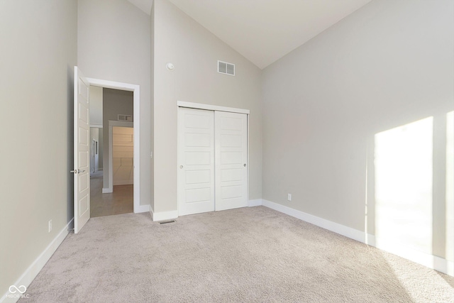 unfurnished bedroom with light carpet, high vaulted ceiling, and a closet