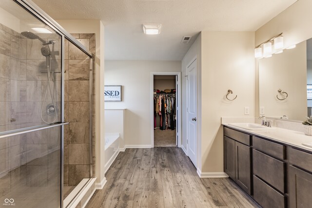 bathroom with hardwood / wood-style floors, vanity, a textured ceiling, and shower with separate bathtub