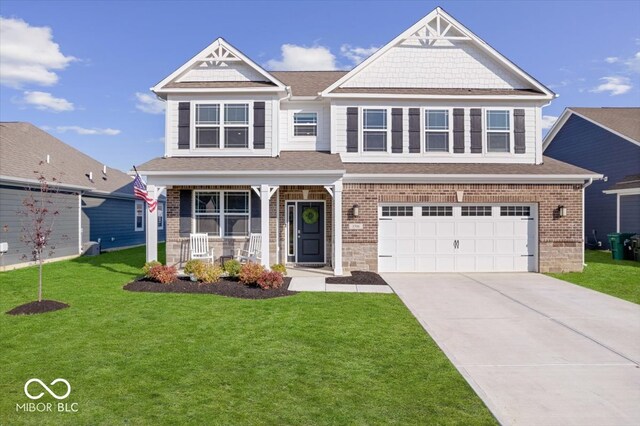 view of front of home with covered porch, a garage, and a front lawn