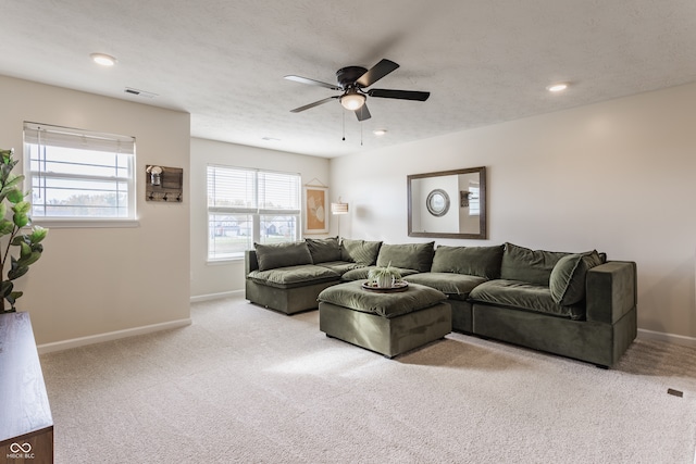 carpeted living room featuring ceiling fan and a textured ceiling