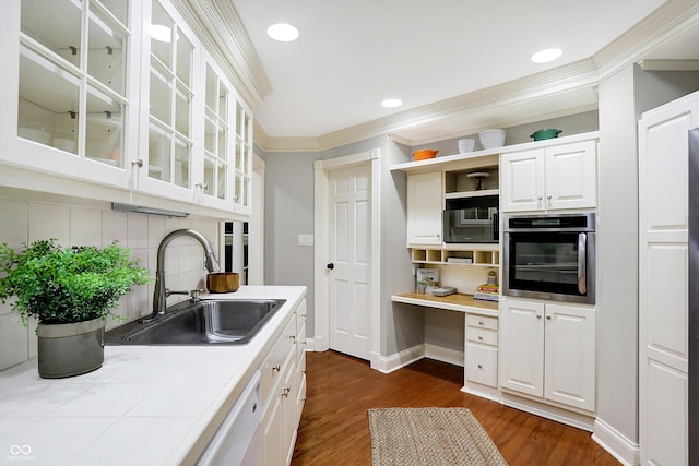 kitchen with tile countertops, stainless steel oven, backsplash, white cabinets, and sink