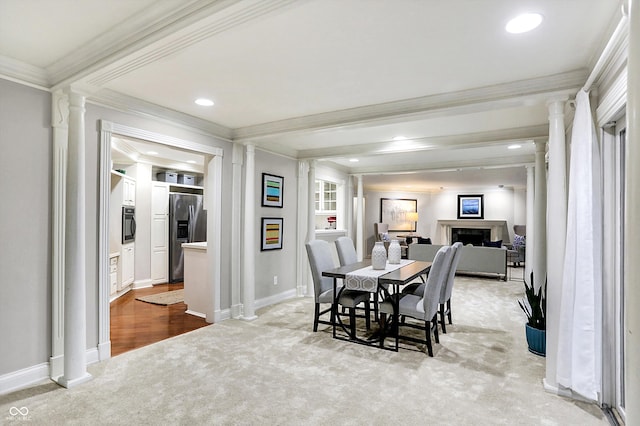 dining room featuring light colored carpet, ornamental molding, and ornate columns