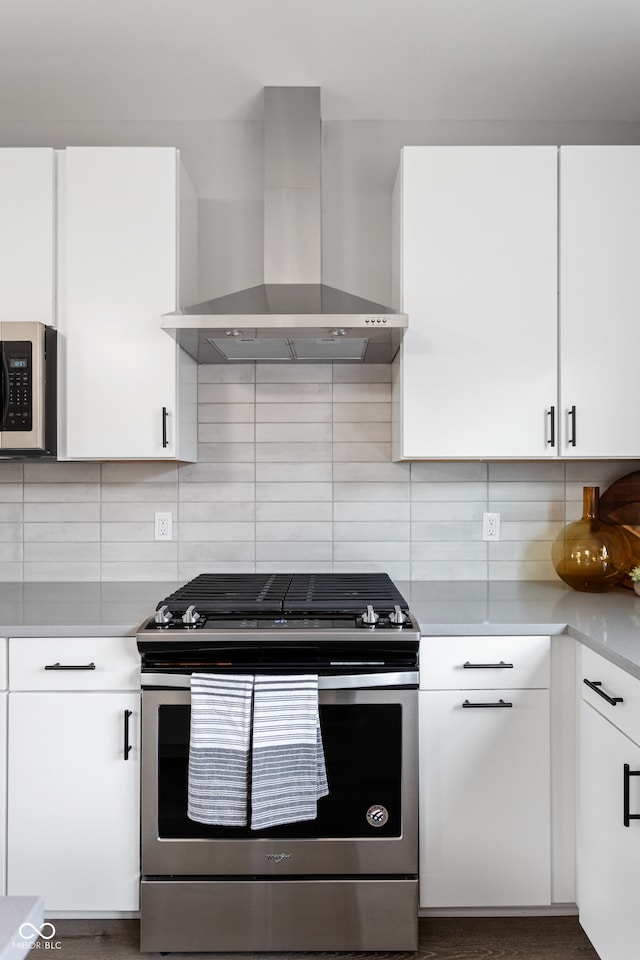 kitchen featuring decorative backsplash, stainless steel appliances, white cabinetry, and wall chimney exhaust hood