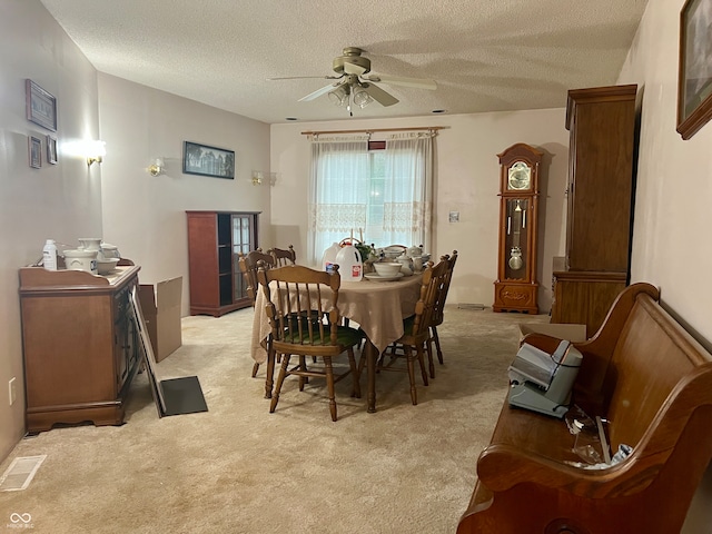 dining room with ceiling fan, light carpet, and a textured ceiling