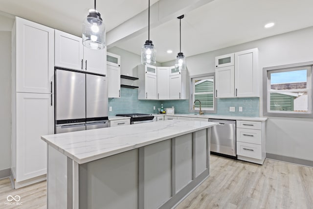 kitchen with white cabinets, appliances with stainless steel finishes, a kitchen island, and a healthy amount of sunlight