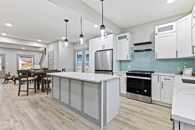 kitchen with appliances with stainless steel finishes, light hardwood / wood-style flooring, white cabinetry, and a kitchen island