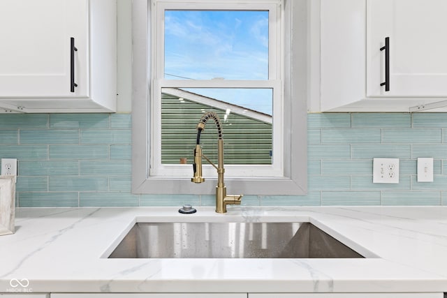 room details with light stone countertops, decorative backsplash, and white cabinets