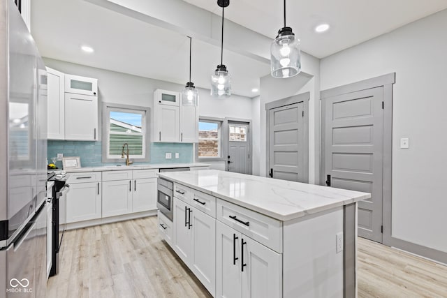 kitchen with a center island, light stone counters, white cabinetry, and tasteful backsplash