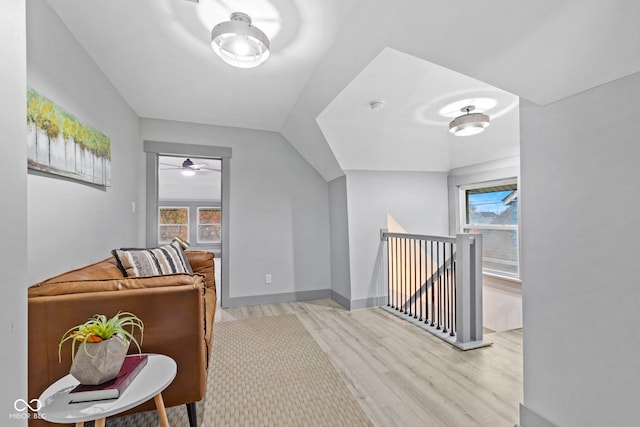 hall with plenty of natural light, lofted ceiling, and light hardwood / wood-style flooring