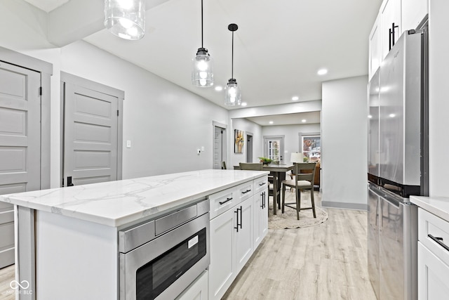 kitchen with light hardwood / wood-style floors, white cabinets, stainless steel appliances, and a kitchen island