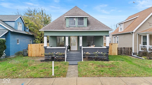 bungalow featuring covered porch and a front yard