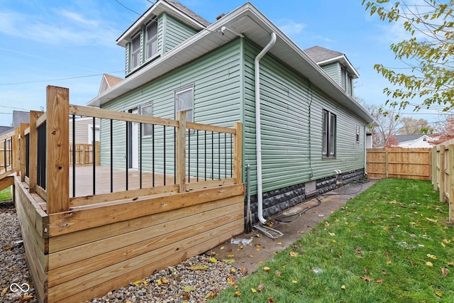 view of side of property featuring a wooden deck and a lawn