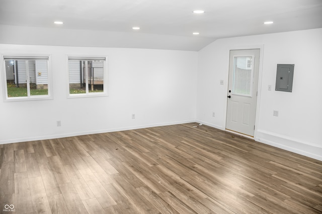 spare room with hardwood / wood-style floors, electric panel, and lofted ceiling