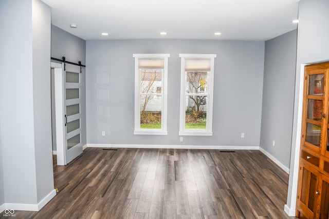 empty room with dark hardwood / wood-style floors and a barn door