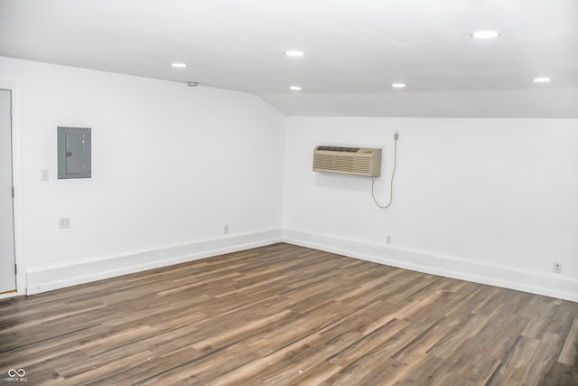 unfurnished room with a wall mounted AC, dark hardwood / wood-style flooring, electric panel, and vaulted ceiling