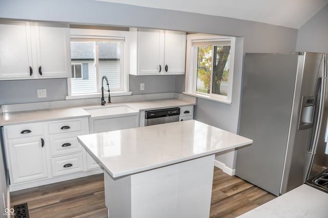 kitchen with appliances with stainless steel finishes, dark hardwood / wood-style flooring, sink, white cabinets, and a center island