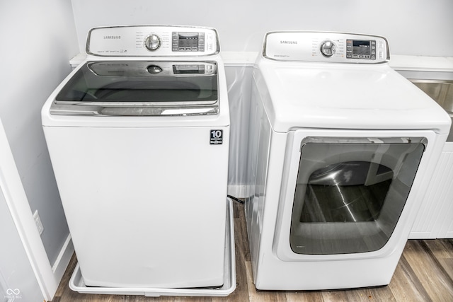 laundry area with hardwood / wood-style flooring and washing machine and clothes dryer