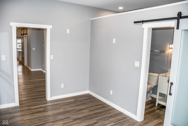 empty room with a barn door and dark wood-type flooring