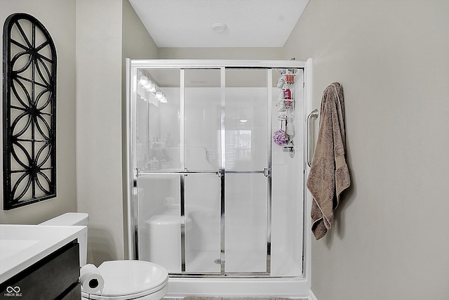 bathroom featuring walk in shower, vanity, a textured ceiling, and toilet