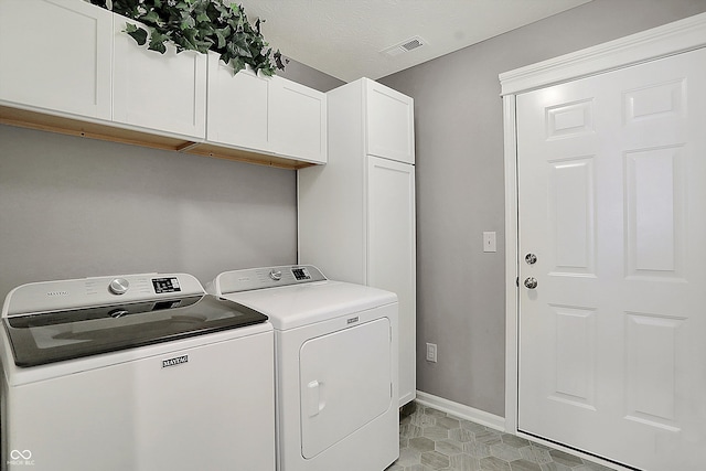 laundry area featuring washing machine and dryer, cabinets, and a textured ceiling