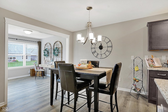 dining area with light hardwood / wood-style floors and an inviting chandelier