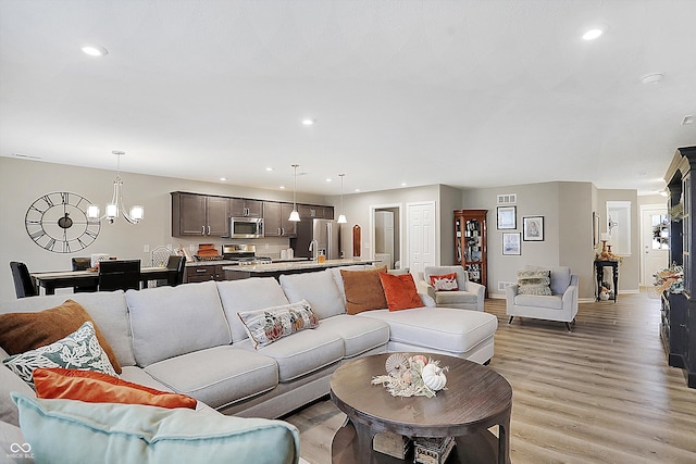 living room with light hardwood / wood-style floors and a notable chandelier