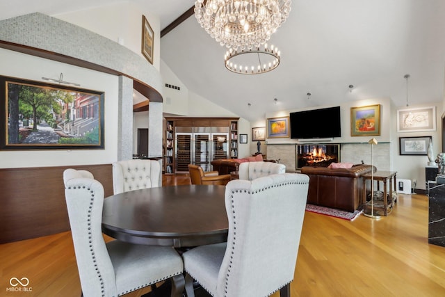 dining space with wood-type flooring, high vaulted ceiling, and a notable chandelier