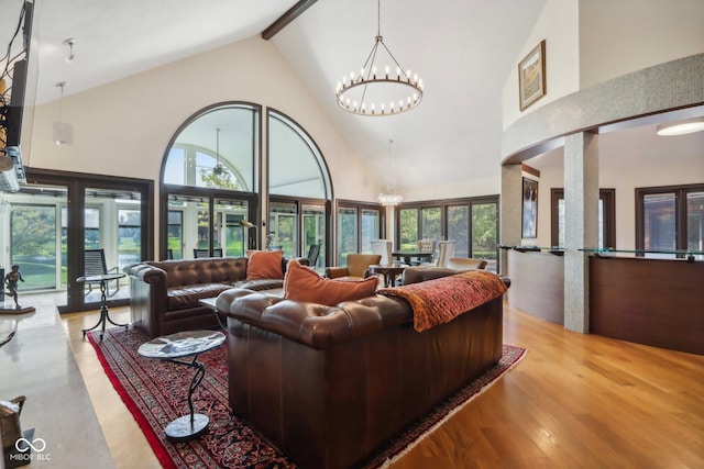 living room featuring beamed ceiling, hardwood / wood-style floors, high vaulted ceiling, and an inviting chandelier