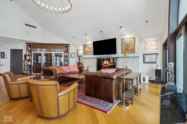 living room featuring a chandelier, light hardwood / wood-style floors, and high vaulted ceiling