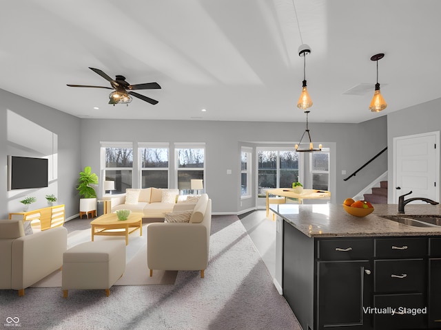 living room with ceiling fan, light colored carpet, and sink