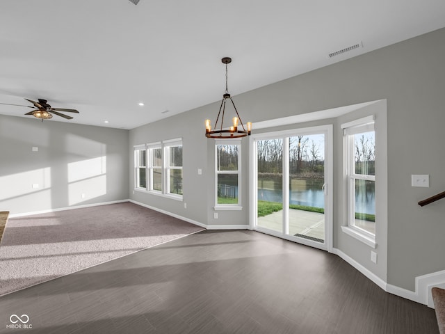 interior space featuring ceiling fan with notable chandelier and a water view