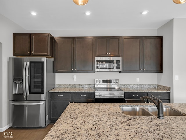 kitchen featuring dark wood-type flooring, sink, light stone countertops, dark brown cabinets, and stainless steel appliances